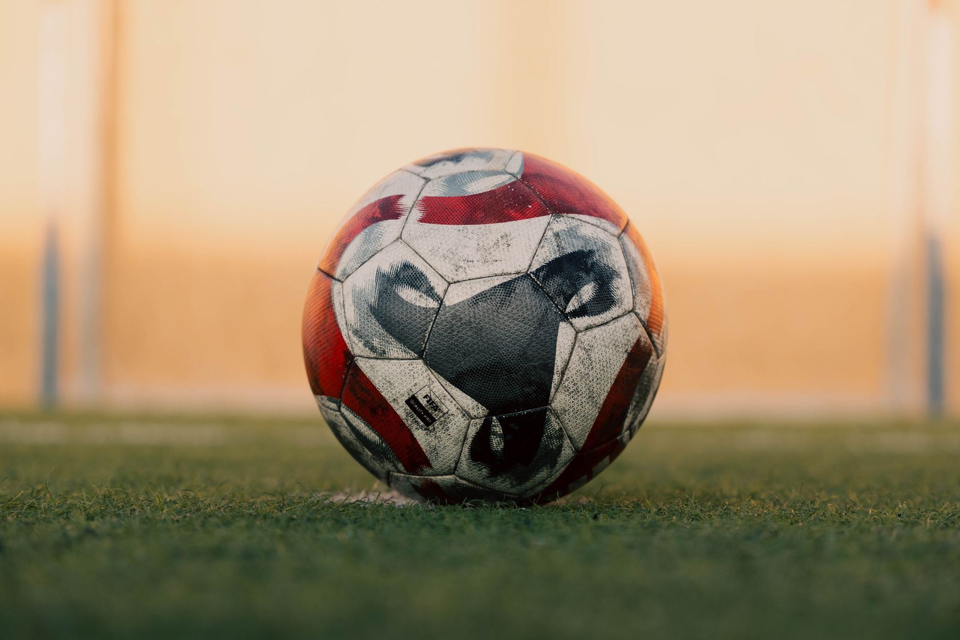 Bola de futebol com guizos parada no gramado sob luz de fim de tarde