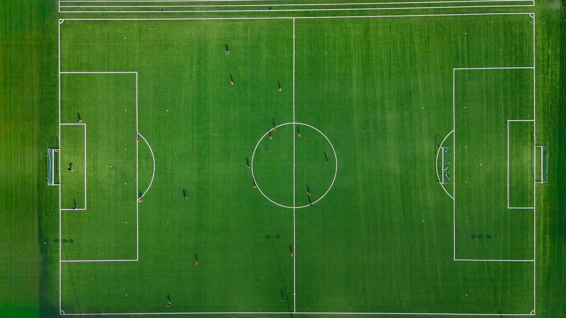 Jogadores jovens em treino de futebol num campo aberto ao fim da tarde