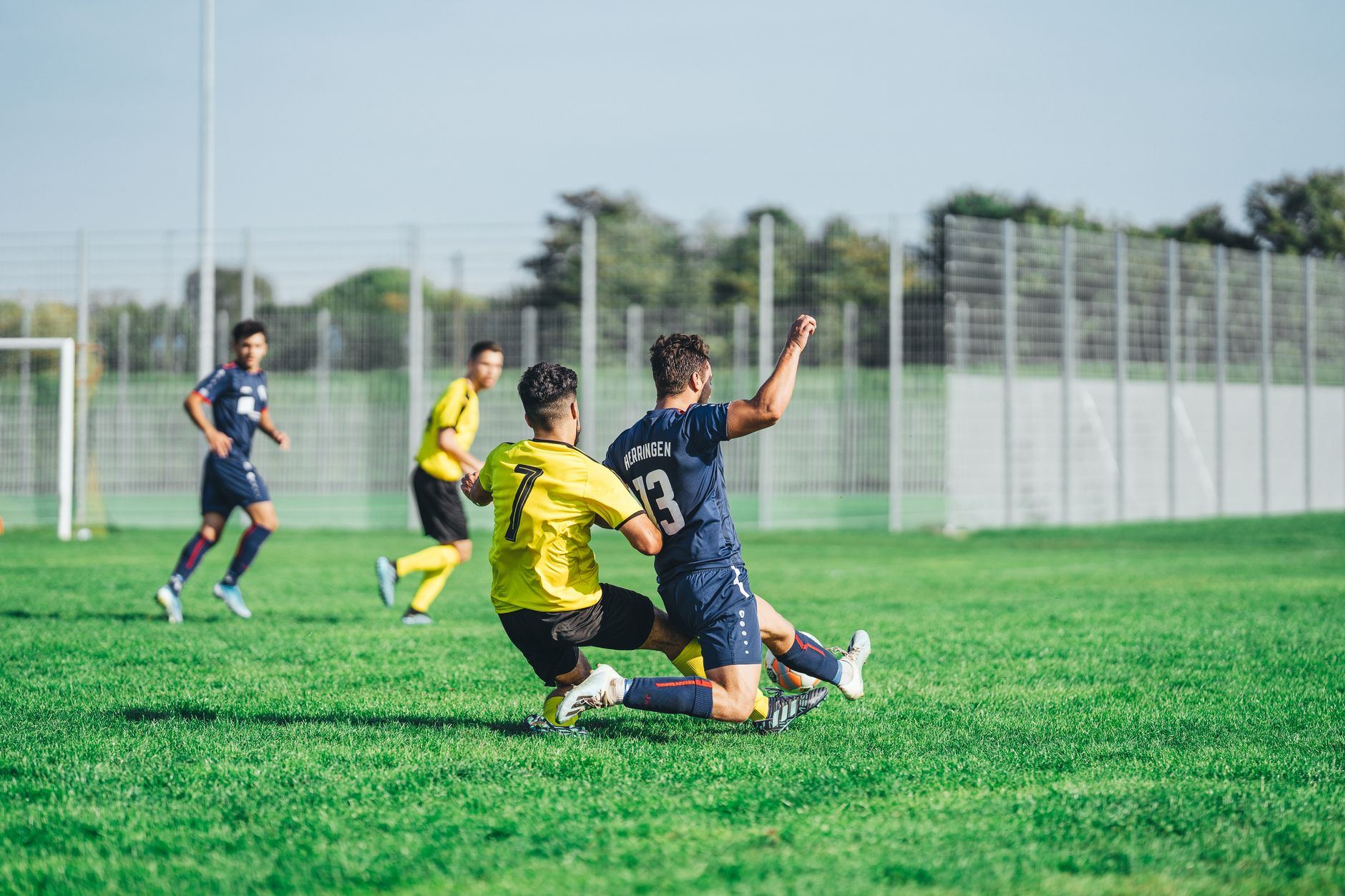 Quatro jogadores disputam a bola em um campo de futebol