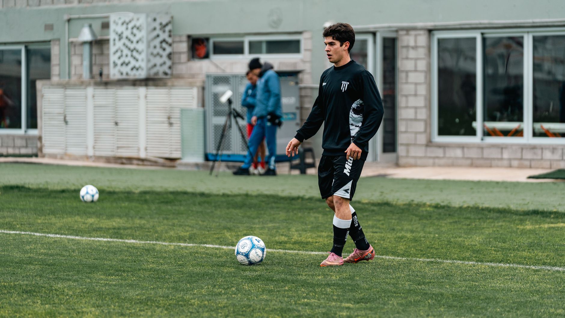 Jovem jogador treinando com bola num campo de futebol