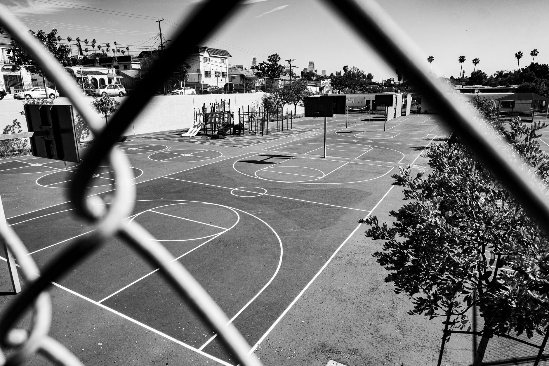 Quadra de basquete ao ar livre com jogadores em partida ao entardecer