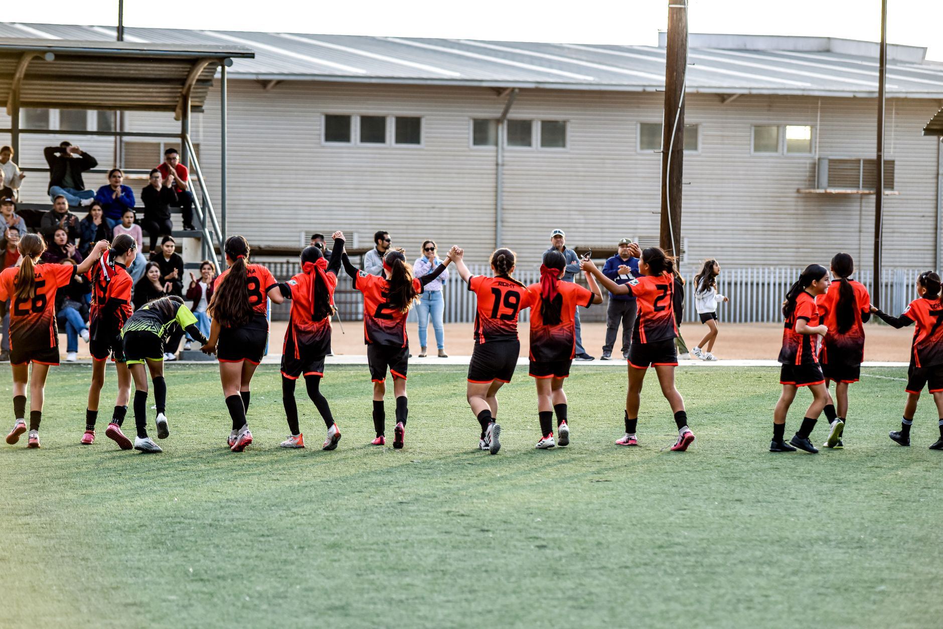 Jovens jogadores comemoram em roda no gramado após vitória
